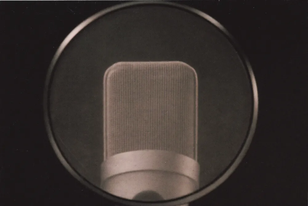 Micro de studio podcast derrière un filtre anti-pop rond