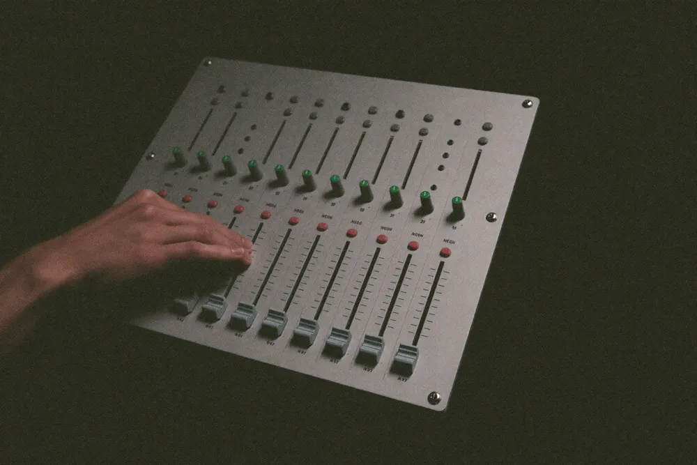 Une main sur les curseurs de la table de mixage
